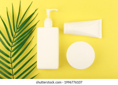 Top View Of Self Tanning Cream And Lotion For Face And Body On Bright Yellow Background With Palm Leaf. Concept Of Self Tanning Products For Beautiful Tan Without Sun And Skin Damage Due To UV Rays