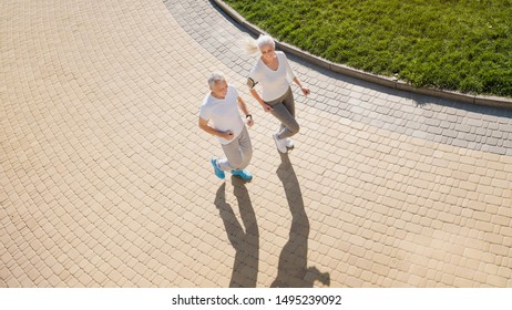 Top View Of Senior Woman And Man Running Doing Fitness Exercises Outdoors