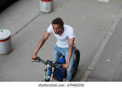Top view of a serious back guy hipster sitting on electric bike and looking into the distance on urban desert road