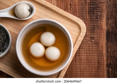 Top view of sesame big tangyuan (tang yuan, glutinous rice dumpling balls) with sweet syrup soup in a bowl on wooden table background for Winter solstice festival food.