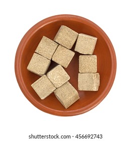 Top View Of Several Beef Flavored Bouillon Cubes Filling A Small Bowl Isolated On A White Background.