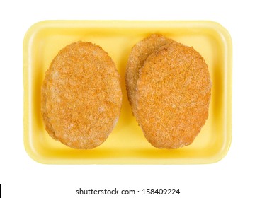 Top View Of Several Pre-cooked Frozen Veal Patties On A Yellow Butchers Tray.