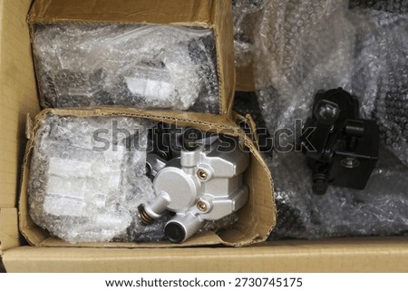 Top view of shipment package box with protective bubble wrap for safe delivery of automotive spare part like metal brake caliper revealing careful preparation and organized logistics distribution