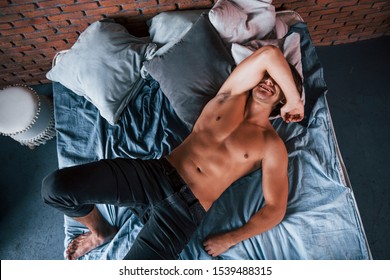 Top view of shirtless sexy man that have a rest alone in his bedroom at morning time.