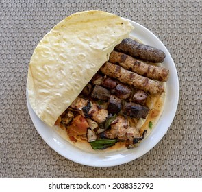 A Top View Of Shish Taouk And Kebab With Cuisine Salad Half-covered By Bread Served In A White Plate