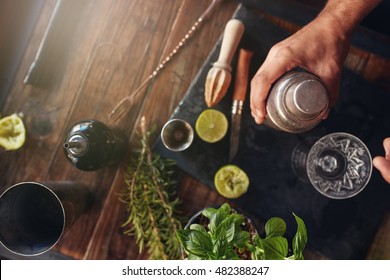 Top View Shot Of Barman Hand Holding Cocktail Shaker On Table With Ingredients.