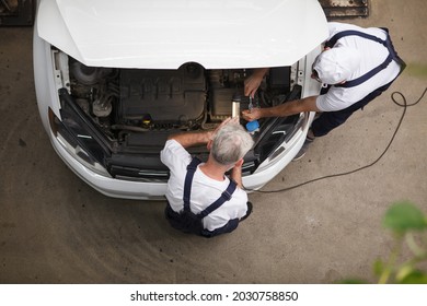 Top View Shot Of Car Repairment Working Under The Hood Of A Car At The Workshop