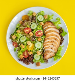 Top View Shot Of Chicken Salad With Several Kinds Of Fresh Vegetable In White Plate On Yellow Background. Natural Authentic Food Concept.