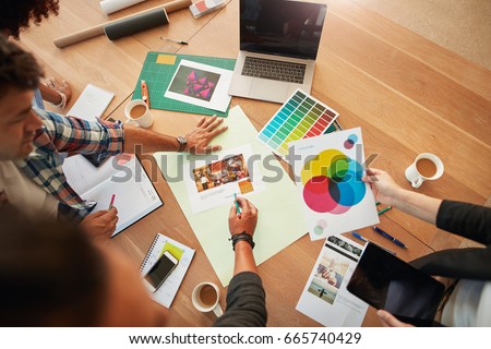 Top view shot of group of creative designers discuss the color palette during meeting. Creative team brainstorming around table.