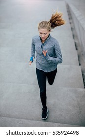 Top View Shot Of Health Conscious Woman Running Upstairs On Steps. Fitness Model Doing Running Workout.