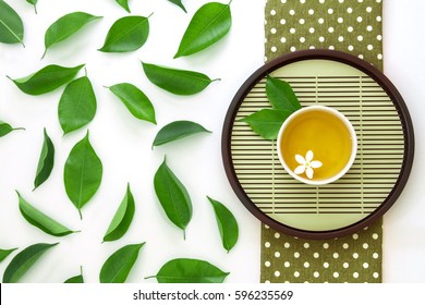 Top view shot of a hot cup of tea with green leaf decoration  on white background , Organic Tea ceremony time concept