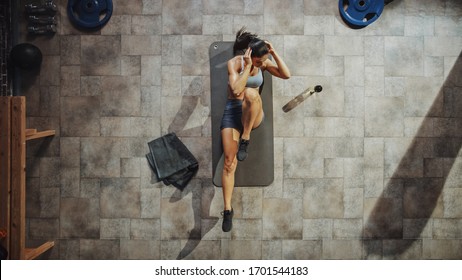 Top View Shot Of Professional Female Bodybuilder Doing Bicycle Crunches While Lying On The Yoga Mat In The Hardcore Gym. Muscular And Athletic Beautiful Woman Muscle, Power And Cardio Workout.