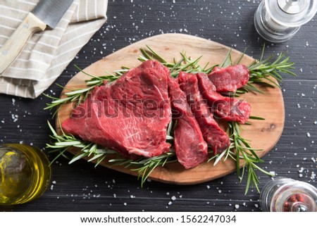 top view shot of a raw italian tagliata, beaf steak., on a wooden chopboard with rosemary and salt with a bottle of olive oil and pink pepper Stock photo © 