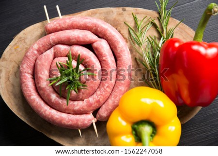 Top  view shot of a raw italian salsiccia, raw sausages on a wooden chopboard with rosemary and a raw yellow and red  pepper Stock photo © 