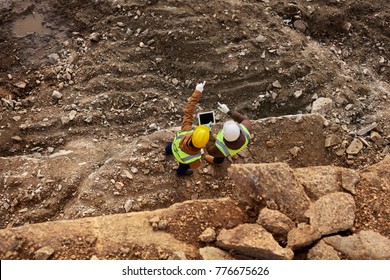Top view shot of two industrial workers wearing reflective jackets standing on mining worksite outdoors using digital tablet, copy space - Shutterstock ID 776675626