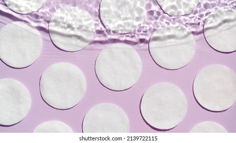 Top View Shot Of Wave Coming From Above Over Cotton Pads Arranged In Rows On Purple Background | Beauty Product Background