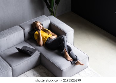 Top View Shot Of A Young Woman Talking With Somebody On Her Handy While In Sofa At Home.