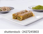 Top view of shredded wheat rolls dessert with pistachio on a white isolated on white background. Local name is burma kadayıf which is a traditional Turkish cuisine dessert with sherbet.