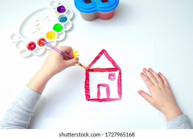 Top View Of Side View Of Hand Of Girl With Pencil Drawing House Of Dream On White Sheet Of Paper.