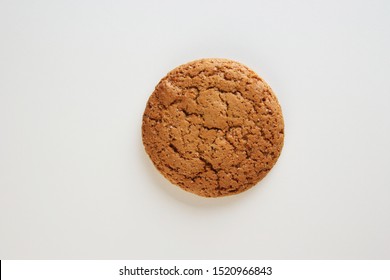 Top view of single freshly baked oatmeal cookie on white background with copy space