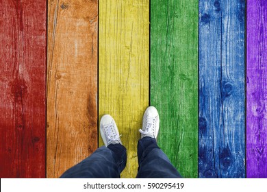 Top view of a single man standing on rainbow gay pride colored wooden floor. Personal perspective used.