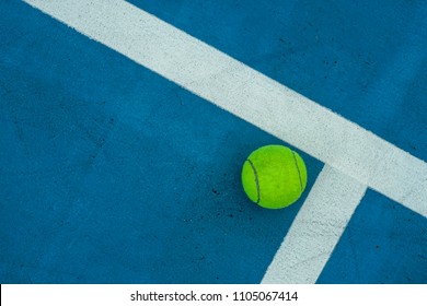 Top View Single Tennis Ball On Blue Tennis Court