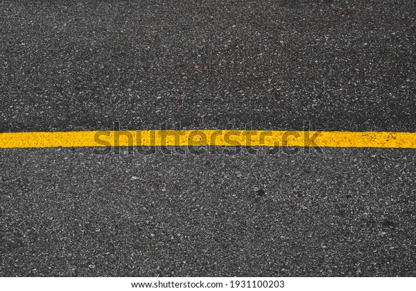 Top view of single yellow road line\
on the asphalt road to apart the lane for car\
driving