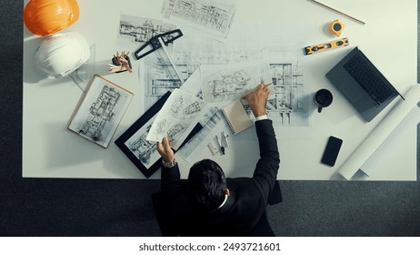 Top view of skilled civil engineer sitting and writing idea while looking at house model. Aerial view of architect or designer planning and thinking about creative building construction. Alimentation. - Powered by Shutterstock