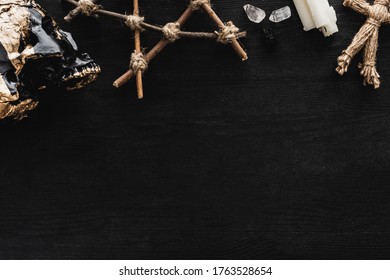 Top View Of Skull, Pentagram, Candles, Crystals And Voodoo Doll On Black