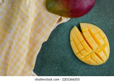 Top View Sliced Mango With A Yellow Kitchen Towel On A Green Background