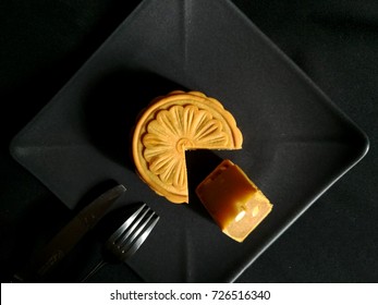 Top View Sliced Moon Cakes Durian Stuffed On Black Plate, Black Background With Knife And Fork