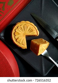 Top View Sliced Moon Cakes Durian Stuffed On Black Plate, Black Background With Knife Fork Parallel Composition And Red Boxes