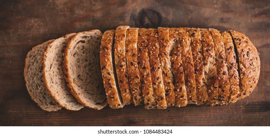 Top view of sliced wholegrain bread on dark ructic wooden  background closeup - Shutterstock ID 1084483424