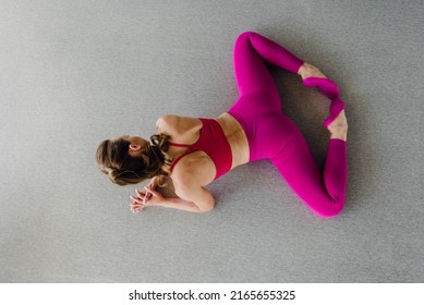 Top view of slim young woman stretching muscles and doing frog exercise