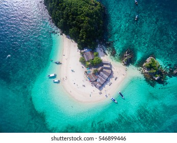 Top view of small isolated tropical island with white sandy beach and blue transparent water and coral reefs. Aerial shooting, speedboats, longtail boats, Khai Nok island, Phuket, Thailand.