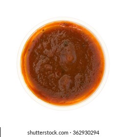 Top View Of A Small Portion Of Marinara Sauce In A Plastic Container Isolated On A White Background.