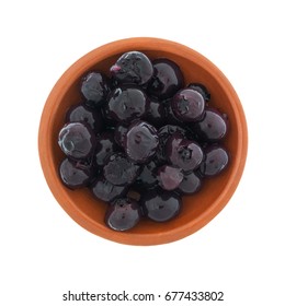 Top view of a small red clay bowl filled with canned blueberries in light syrup isolated on a white background.