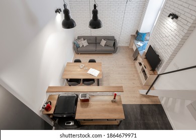 Top View Of Small And Stylish Loft Apartment With Brick Walls, Wooden Floor And Furniture And Kitchen, Dining Area And Living Room In One