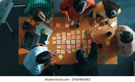 Top view of smart diverse business team working together and clapping hand while brainstorming marketing idea or creative startup project by using sticky notes and stick at meeting table. Convocation. - Powered by Shutterstock