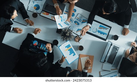 Top view of smart manager looking at financial statistic on tablet at meeting room. Group of diverse business people working together to analyze investment data on table with notebook. Directorate. - Powered by Shutterstock