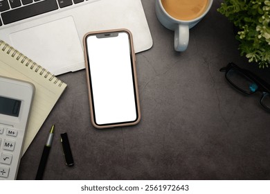 Top view smartphone with empty screen, laptop, coffee cup and calculator on dark textured surface