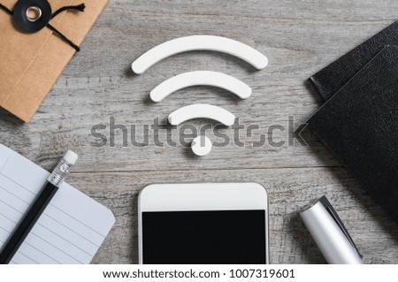 Top view of smartphone on desk searches a free wifi connection available. High angle view of smart phone with white wi-fi sign on top. Internet technology and networking concept.
