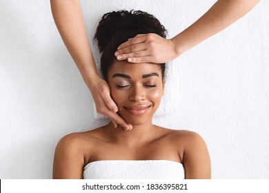 Top View Of Smiling Black Lady Getting Lifting Face Massage On White Background. Relaxed African American Young Woman With Closed Eyes Enjoying Anti-aging Face Procedure At Spa, View Above