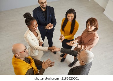 Top view of smiling diverse business partners handshake greet get acquainted at office team meeting. Senior businessman shake hand congratulate ethnic female colleague with promotion or success. - Shutterstock ID 2198620001