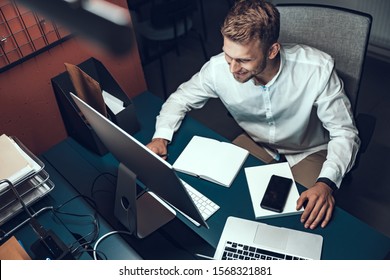 Top view of smiling male worker busy working on computer