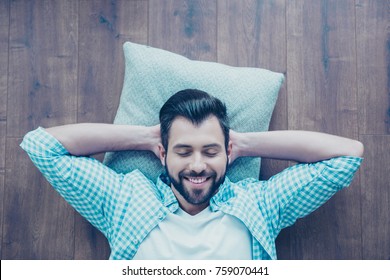 Top View Of Smiling Man With Bristle, Lying On The Floor With Closed Eyes, Hands Behind The Head, He Is Dreaming About Vacation, Having Rest From Work