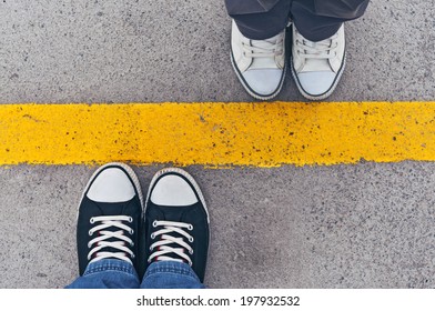 Top view of sneakers from above, male and female feet in casual footwear standing at dividing frontier line.