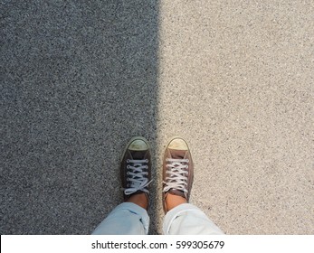 Top View Of Sneakers On The Asphalt Road,with Dark Side And Bright Side.           