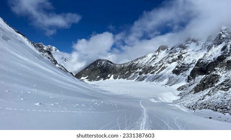 Top view of the snow-covered Delaunay pass. Climbing Mount Belukha. Altai Mountains. Beautiful mountain landscape. Amazing natural background. Blue sky and white clouds.