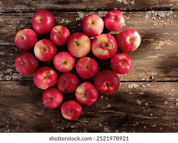 Top view of some beautiful red apples arranged in the shape of a heart on an old wooden table. - Powered by Shutterstock